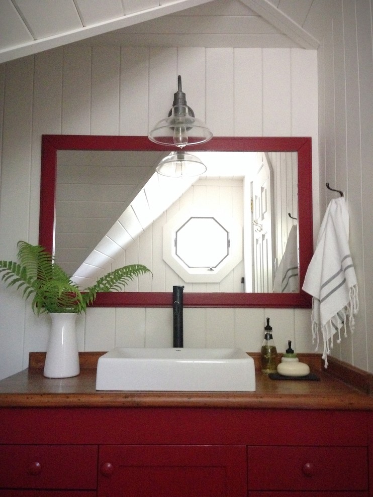 Imagen de cuarto de baño rústico de tamaño medio con lavabo sobreencimera, armarios con paneles lisos, puertas de armario rojas, encimera de madera, paredes blancas y suelo de madera en tonos medios
