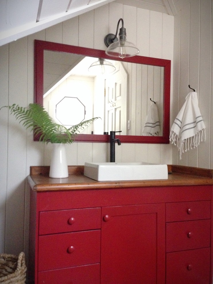 Foto de cuarto de baño rural de tamaño medio con lavabo sobreencimera, armarios con paneles lisos, puertas de armario rojas, encimera de madera, suelo de madera en tonos medios y paredes blancas