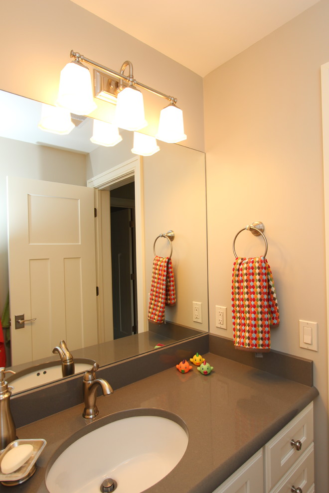 Example of a mid-sized transitional kids' brown tile and porcelain tile porcelain tile bathroom design in Grand Rapids with an undermount sink, recessed-panel cabinets, white cabinets, quartz countertops, a two-piece toilet and beige walls