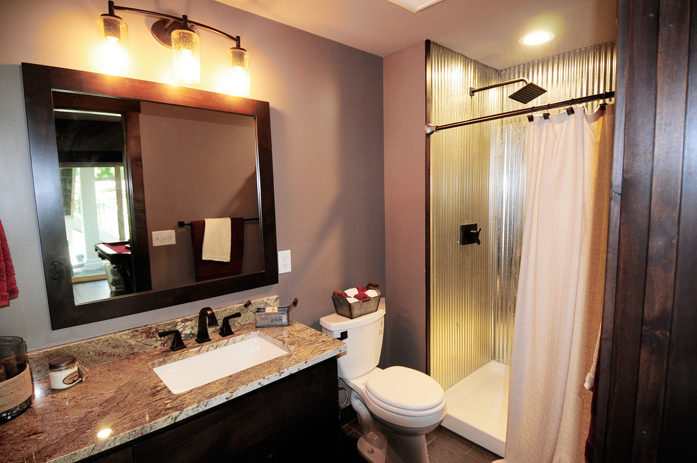 Example of a mid-sized mountain style 3/4 porcelain tile and brown floor bathroom design in Minneapolis with shaker cabinets, dark wood cabinets, a two-piece toilet, beige walls, an undermount sink and granite countertops