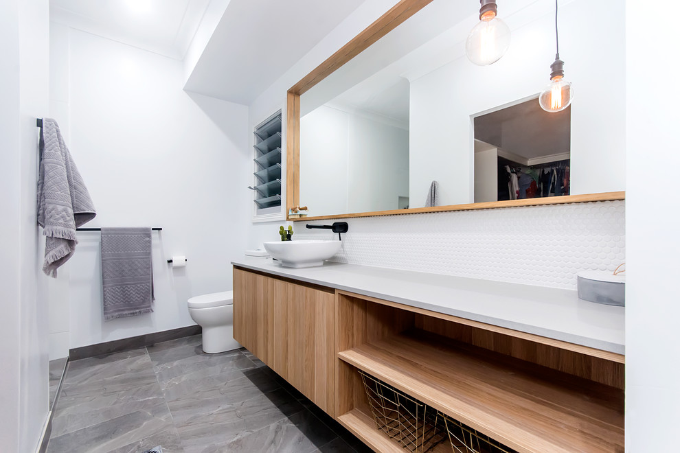 This is an example of a medium sized urban ensuite bathroom in Other with flat-panel cabinets, light wood cabinets, a walk-in shower, a one-piece toilet, white tiles, ceramic tiles, white walls, ceramic flooring, a vessel sink, granite worktops, grey floors, an open shower, grey worktops, a wall niche, a single sink and a floating vanity unit.