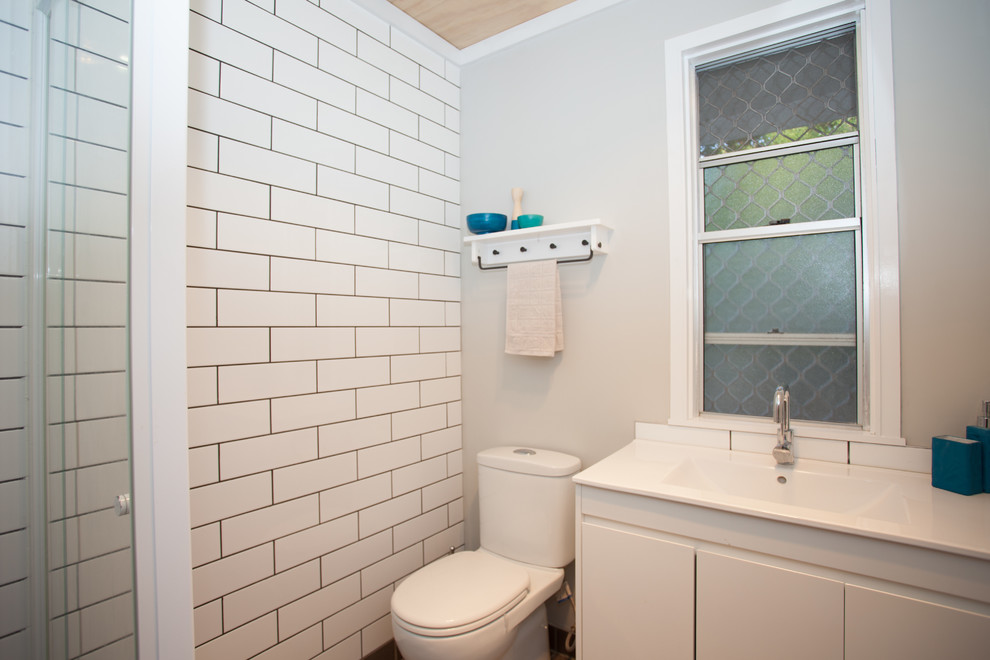 На фото: маленькая детская ванная комната в классическом стиле с белыми фасадами, унитазом-моноблоком, белой плиткой, плиткой кабанчик, серыми стенами, полом из керамической плитки, монолитной раковиной, столешницей из ламината, серым полом, душем с распашными дверями, белой столешницей и тумбой под одну раковину для на участке и в саду с