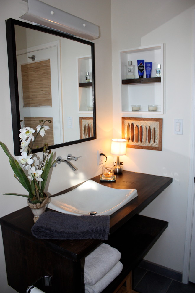 Modern inredning av ett en-suite badrum, med öppna hyllor, skåp i mellenmörkt trä, en dusch i en alkov, en toalettstol med separat cisternkåpa, vit kakel, keramikplattor, vita väggar, ett fristående handfat och träbänkskiva