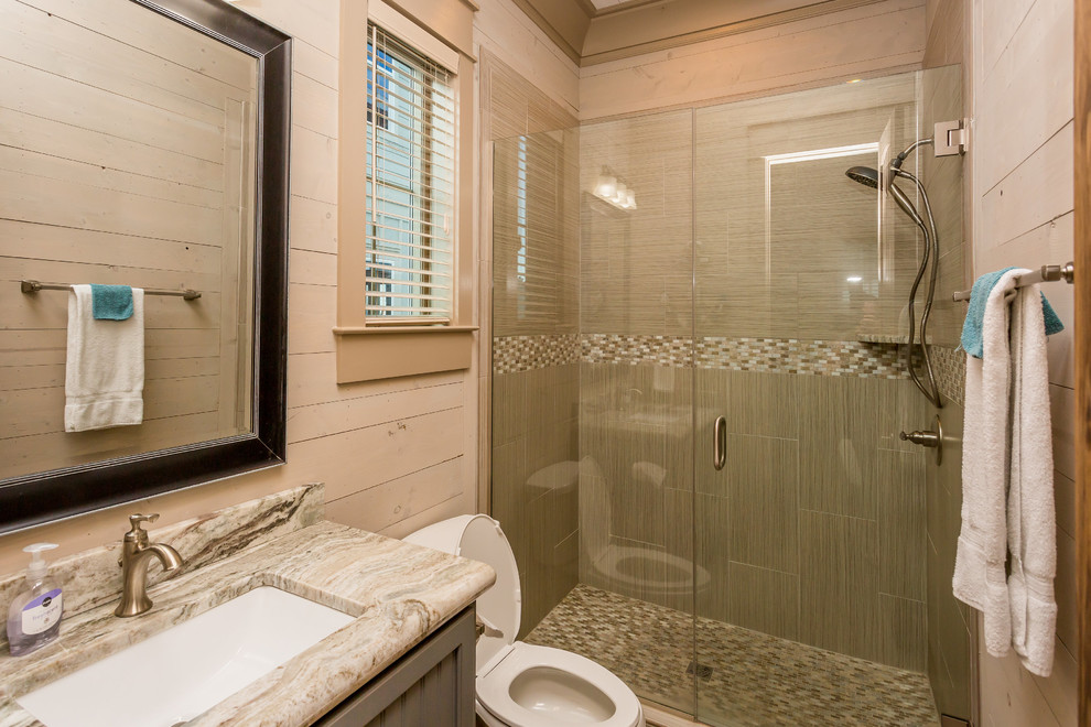 Réalisation d'une salle de bain marine avec des portes de placard grises, une douche ouverte, un carrelage marron, un plan de toilette en granite, un lavabo encastré et un mur beige.