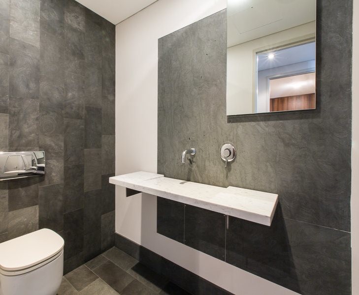 Пример оригинального дизайна: главная ванная комната среднего размера в современном стиле с мраморной столешницей, белыми фасадами, инсталляцией, плиткой из известняка, серыми стенами, бетонным полом, настольной раковиной и серым полом