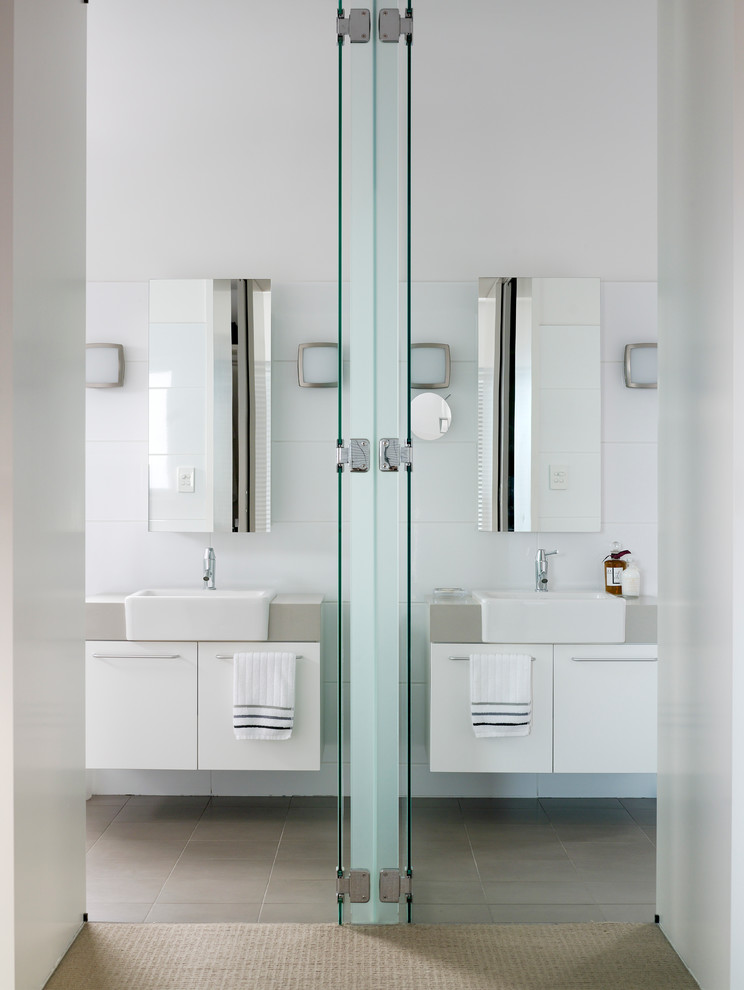 Imagen de cuarto de baño principal y rectangular actual con paredes blancas, armarios con paneles lisos, puertas de armario blancas, baldosas y/o azulejos blancos y encimeras grises