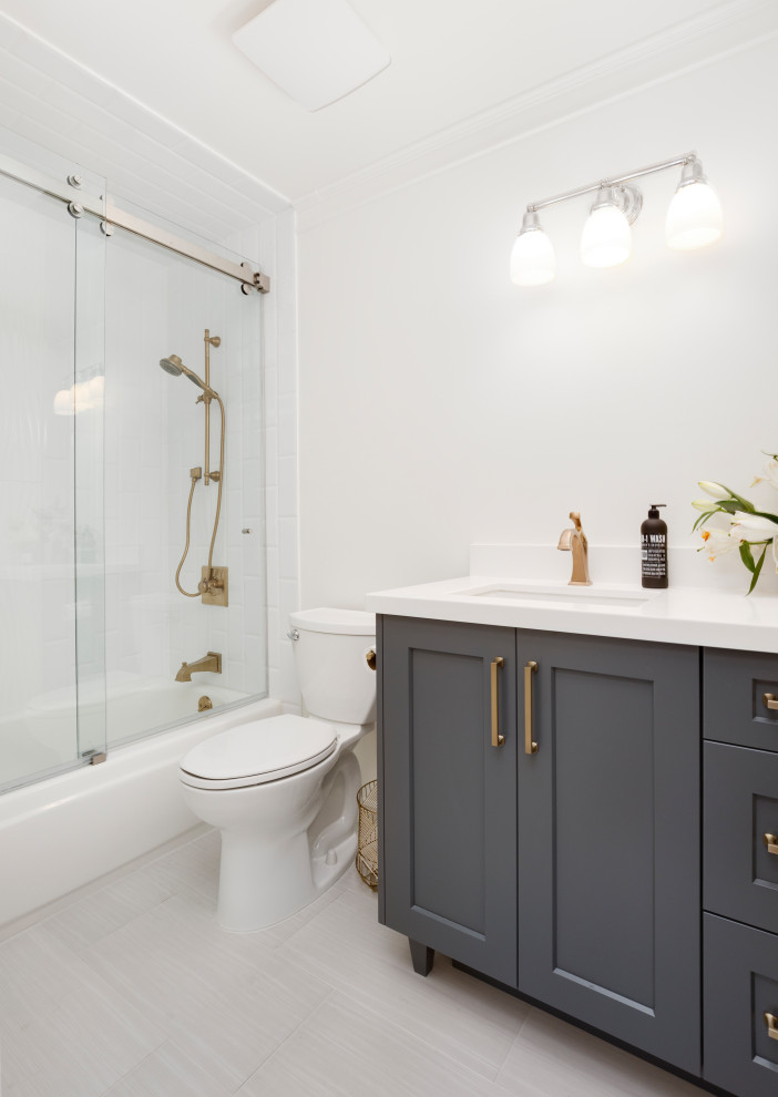 Стильный дизайн: маленькая ванная комната в стиле модернизм с фасадами в стиле шейкер, серыми фасадами, ванной в нише, душем над ванной, раздельным унитазом, белой плиткой, керамогранитной плиткой, белыми стенами, полом из керамогранита, врезной раковиной, столешницей из искусственного кварца, серым полом, душем с раздвижными дверями, белой столешницей и душевой кабиной для на участке и в саду - последний тренд