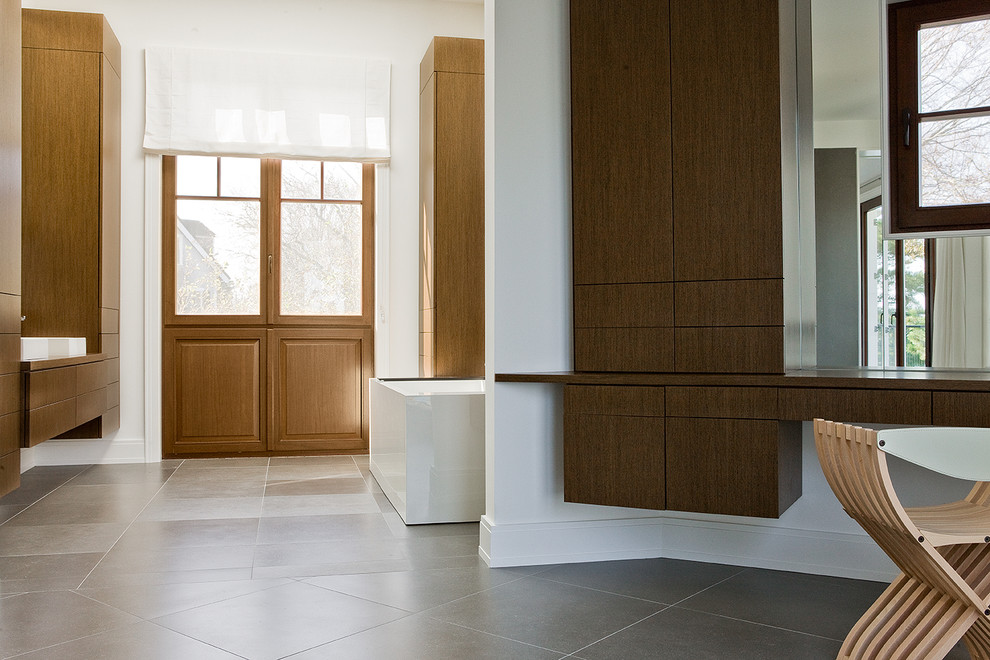 Inspiration for a large contemporary ensuite bathroom in Boston with flat-panel cabinets, medium wood cabinets, a freestanding bath, grey tiles, stone tiles, white walls, a vessel sink and wooden worktops.