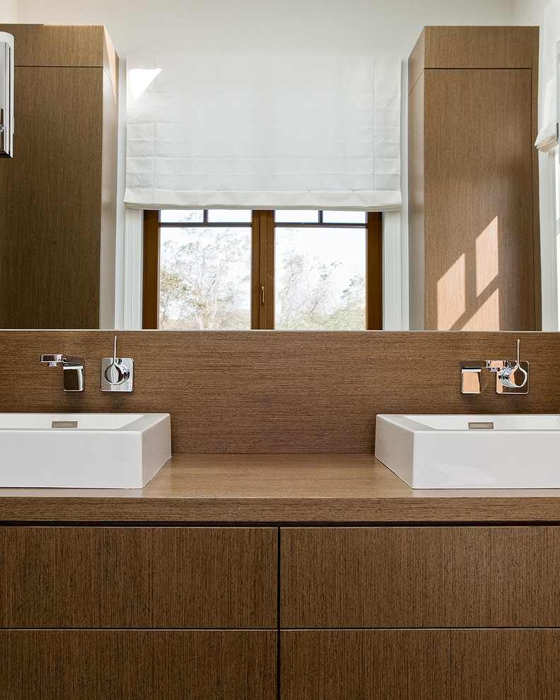 На фото: главная ванная комната в современном стиле с настольной раковиной, плоскими фасадами, темными деревянными фасадами и столешницей из дерева с