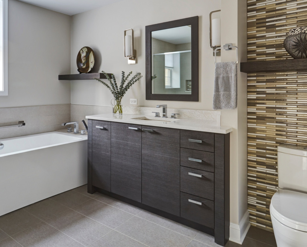 Photo of a large contemporary ensuite bathroom in Chicago with flat-panel cabinets, dark wood cabinets, a freestanding bath, a built-in shower, a two-piece toilet, grey tiles, porcelain tiles, beige walls, porcelain flooring, a submerged sink, engineered stone worktops, grey floors, a hinged door and beige worktops.