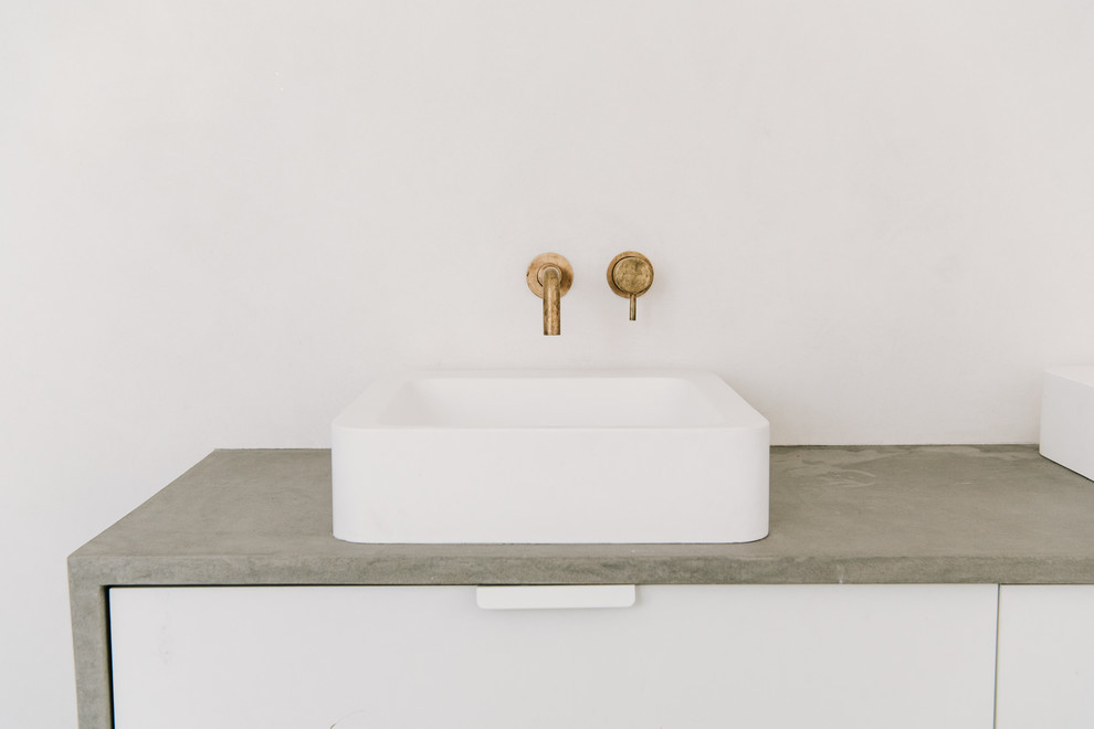 Idée de décoration pour une salle de bain minimaliste de taille moyenne pour enfant avec un placard à porte plane, des portes de placard blanches, une baignoire indépendante, un carrelage beige, carreaux de ciment au sol, un plan de toilette en béton et un sol gris.