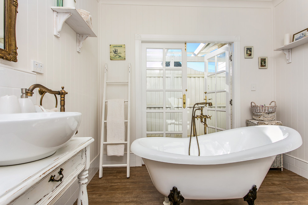 Réalisation d'une salle de bain principale champêtre avec une baignoire sur pieds, un mur blanc, une vasque et un plan de toilette en bois.