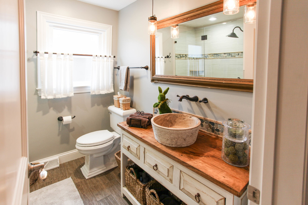 Bathroom - mid-sized farmhouse master gray tile and porcelain tile porcelain tile and brown floor bathroom idea in Chicago with furniture-like cabinets, distressed cabinets, a two-piece toilet, green walls, a vessel sink and wood countertops