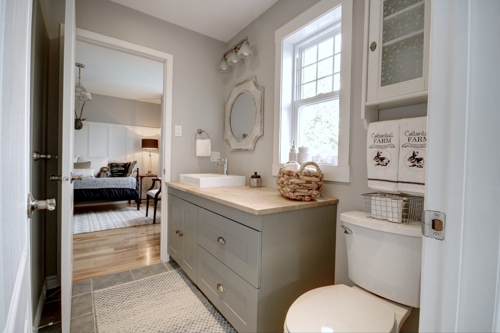 Photo of a medium sized country family bathroom in Other with shaker cabinets, green cabinets, a two-piece toilet, grey walls, ceramic flooring, a vessel sink, wooden worktops, grey floors and beige worktops.