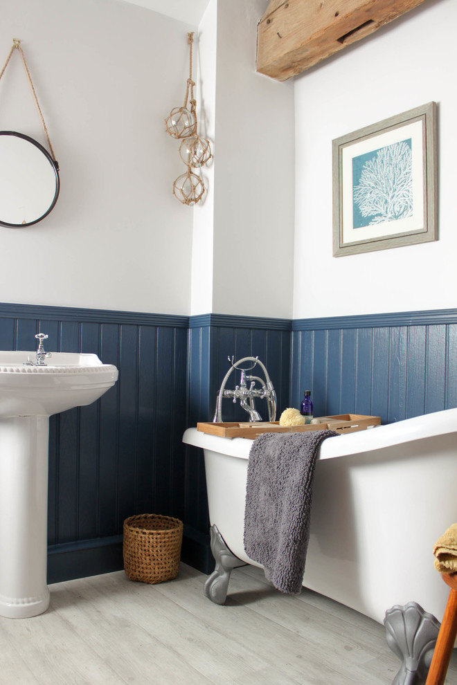Cette image montre une petite salle de bain rustique pour enfant avec une baignoire indépendante, WC séparés, un mur bleu, sol en stratifié, un lavabo de ferme et un sol gris.