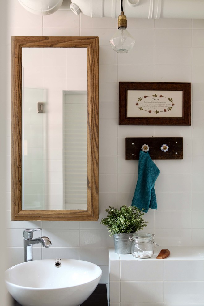 Modelo de cuarto de baño actual con baldosas y/o azulejos blancos, baldosas y/o azulejos de cemento, paredes blancas, lavabo sobreencimera y encimeras negras