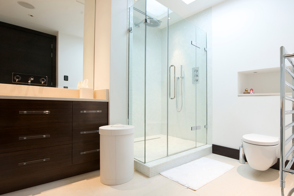 Modelo de cuarto de baño contemporáneo de tamaño medio con ducha esquinera, sanitario de pared, paredes blancas, suelo de baldosas de porcelana y lavabo encastrado