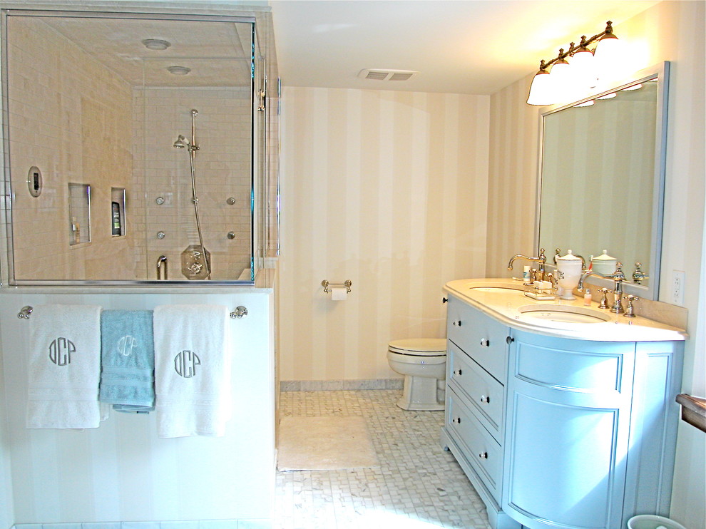 Diseño de cuarto de baño principal de estilo de casa de campo grande con lavabo bajoencimera, armarios con paneles empotrados, puertas de armario azules, ducha esquinera, sanitario de dos piezas, baldosas y/o azulejos grises y paredes multicolor