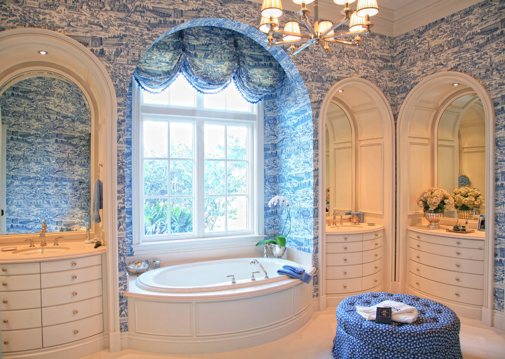 This is an example of a victorian bathroom in Miami with a submerged sink, flat-panel cabinets, beige cabinets, a built-in bath, beige tiles and blue walls.