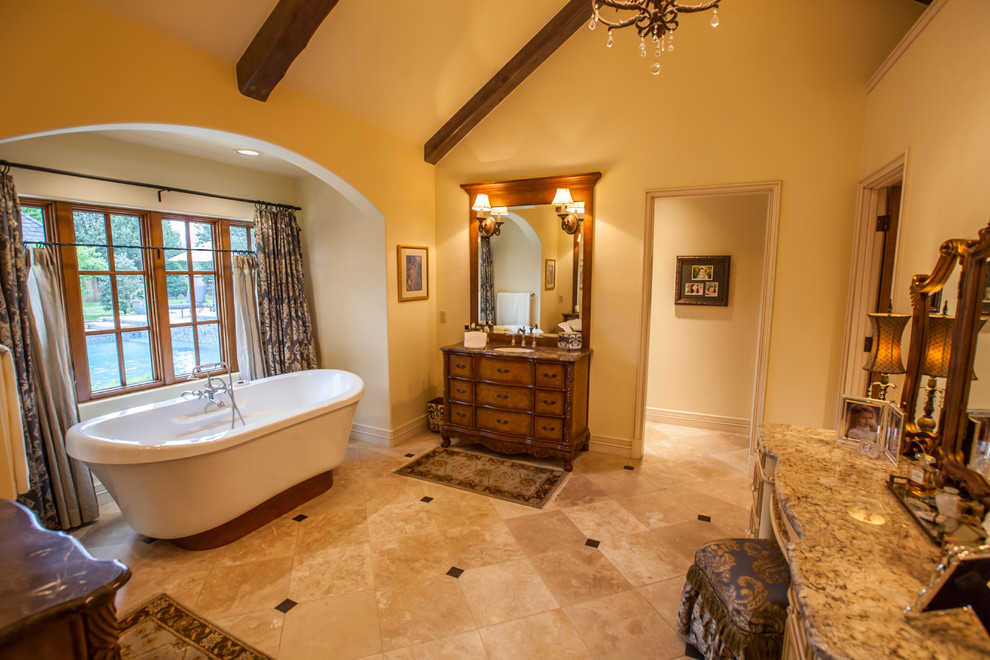 Inspiration for a large classic ensuite bathroom in Oklahoma City with freestanding cabinets, medium wood cabinets, a freestanding bath, beige tiles, ceramic tiles, beige walls, ceramic flooring, a submerged sink and granite worktops.