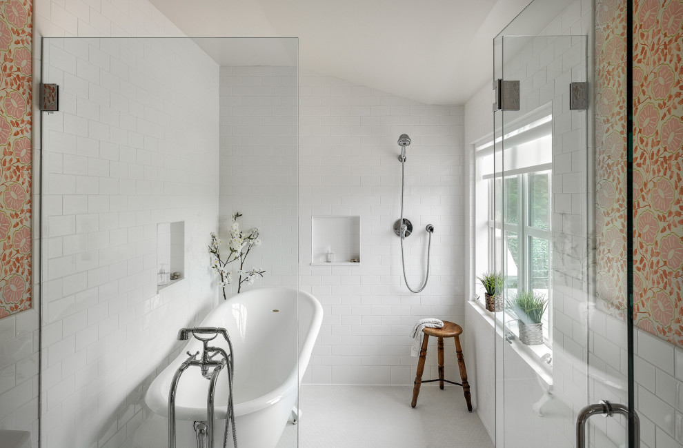 Lantlig inredning av ett badrum, med ett badkar med tassar, våtrum, vit kakel, tunnelbanekakel, flerfärgade väggar, grått golv och dusch med gångjärnsdörr