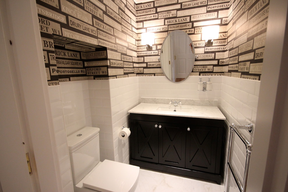 Modelo de cuarto de baño tradicional pequeño con armarios estilo shaker, puertas de armario negras, sanitario de pared, baldosas y/o azulejos blancos, baldosas y/o azulejos de cemento, lavabo encastrado y encimera de mármol