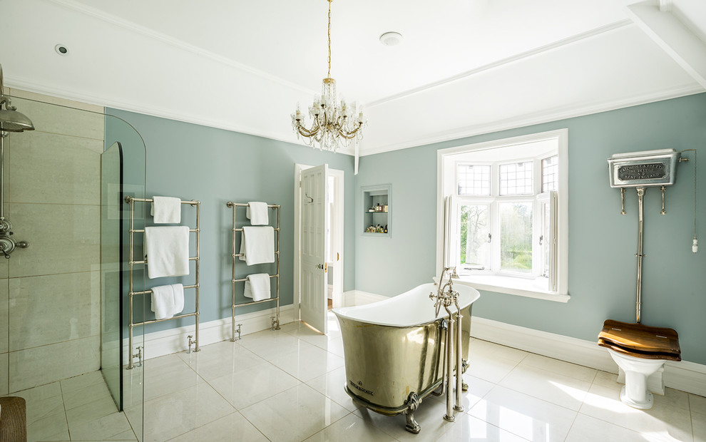 Immagine di una stanza da bagno classica con vasca con piedi a zampa di leone, doccia a filo pavimento, WC a due pezzi, piastrelle beige, pareti blu e doccia aperta