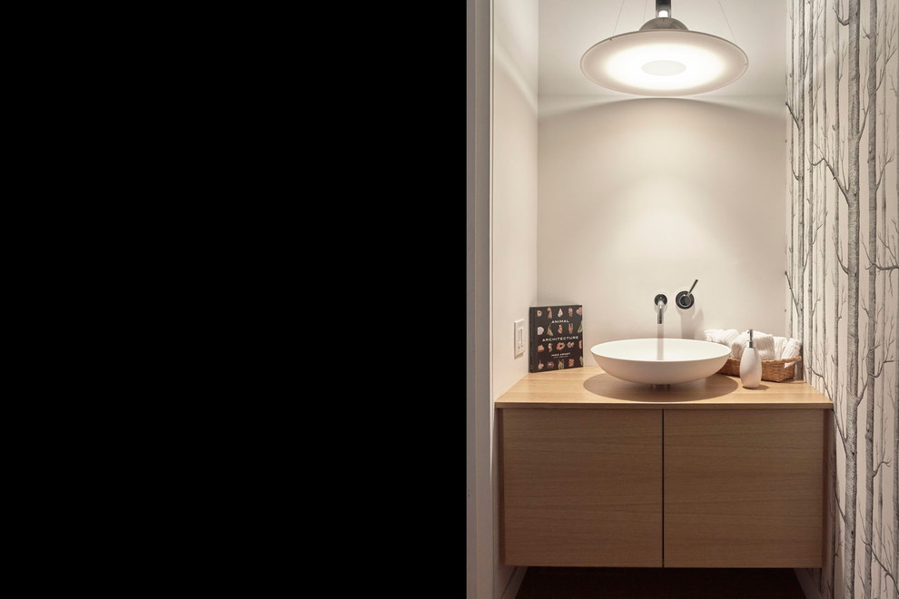 Ejemplo de cuarto de baño moderno pequeño con armarios con paneles lisos, puertas de armario de madera clara, paredes blancas, suelo de madera clara, lavabo sobreencimera y encimera de madera