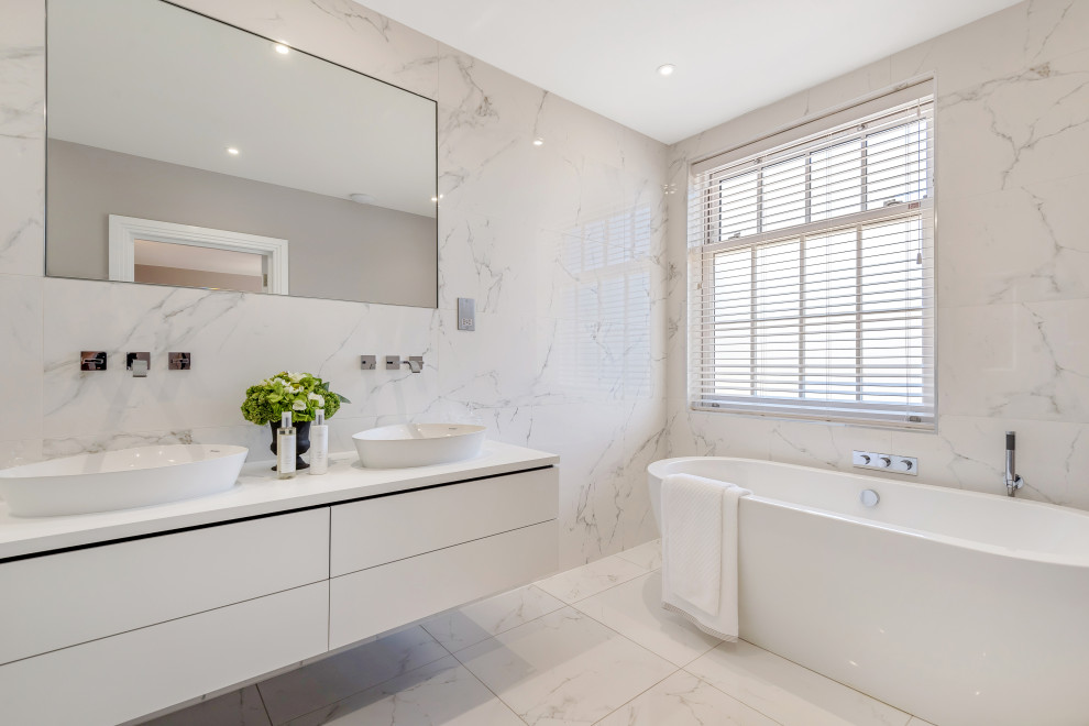 Modernes Badezimmer mit flächenbündigen Schrankfronten, weißen Schränken, freistehender Badewanne, Aufsatzwaschbecken, weißem Boden und weißer Waschtischplatte in Hampshire