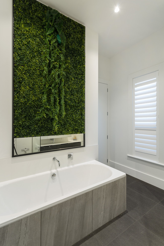 На фото: ванная комната в стиле модернизм с накладной ванной и белыми стенами с