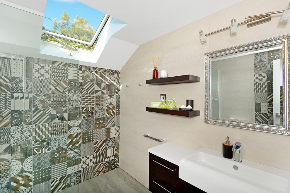 Design ideas for a small contemporary bathroom in Auckland with flat-panel cabinets, dark wood cabinets, a built-in shower, multi-coloured tiles, porcelain tiles, beige walls, cement flooring, a trough sink and laminate worktops.