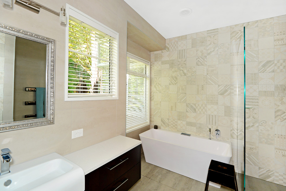 Cette image montre une petite salle de bain design en bois foncé avec un placard à porte plane, une baignoire indépendante, une douche à l'italienne, un carrelage multicolore, des carreaux de porcelaine, un mur beige, une grande vasque et un plan de toilette en stratifié.