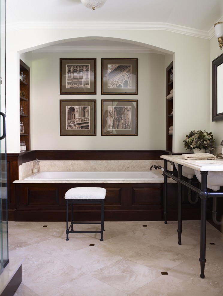 Immagine di una stanza da bagno classica con lavabo a consolle, vasca da incasso e piastrelle in travertino