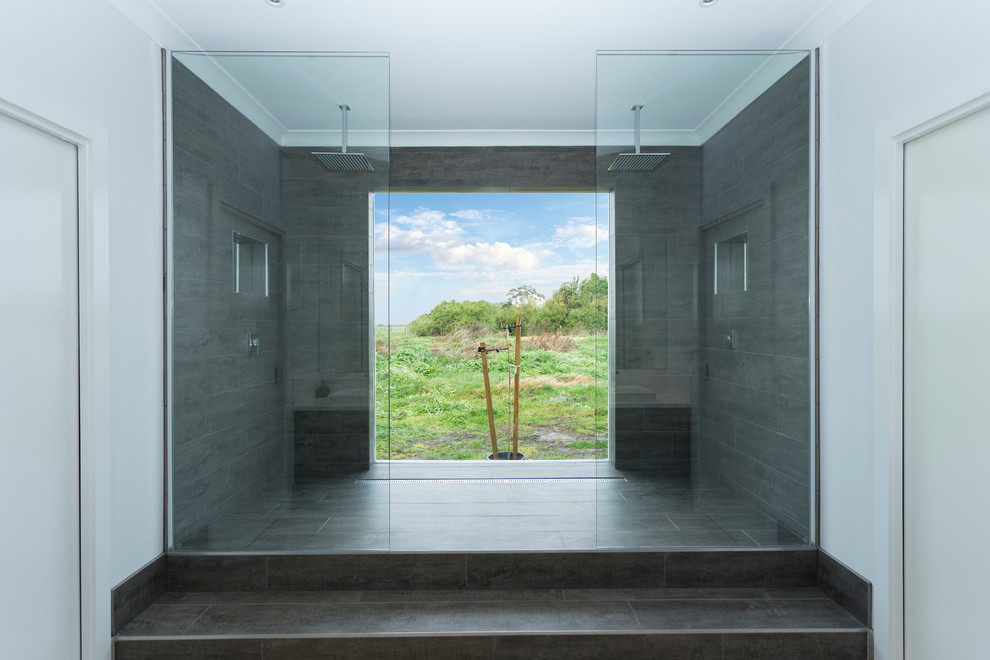 Cette image montre une salle de bain principale minimaliste de taille moyenne avec une douche double, un carrelage gris, du carrelage en travertin, aucune cabine, un mur blanc, un sol en carrelage de porcelaine et un sol gris.