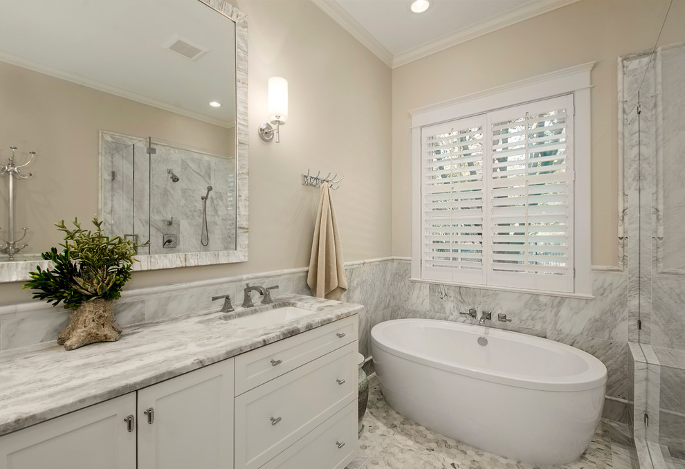 Example of a large transitional master gray tile and stone tile mosaic tile floor bathroom design in Dallas with shaker cabinets, white cabinets, a one-piece toilet, gray walls, an undermount sink and marble countertops