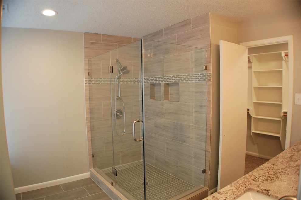 Foto på ett funkis en-suite badrum, med en hörndusch, grå kakel, porslinskakel, grå väggar, klinkergolv i porslin, grått golv och dusch med gångjärnsdörr