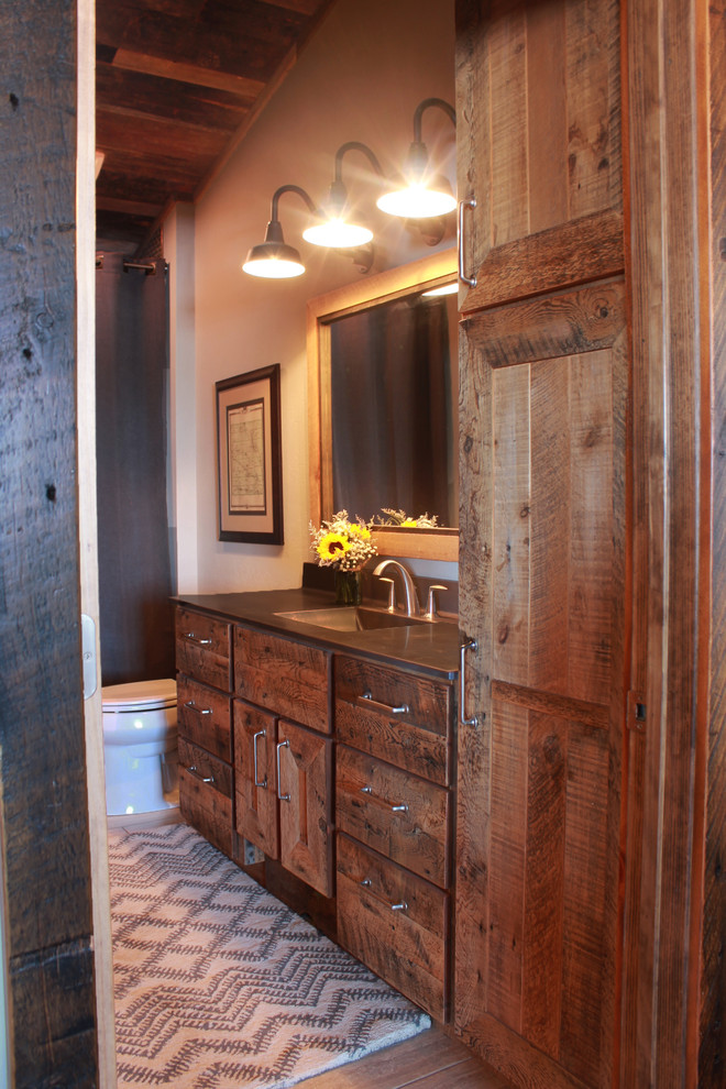 Bathroom - mid-sized rustic master limestone floor bathroom idea in Other with an integrated sink, recessed-panel cabinets, distressed cabinets, concrete countertops, a two-piece toilet and gray walls