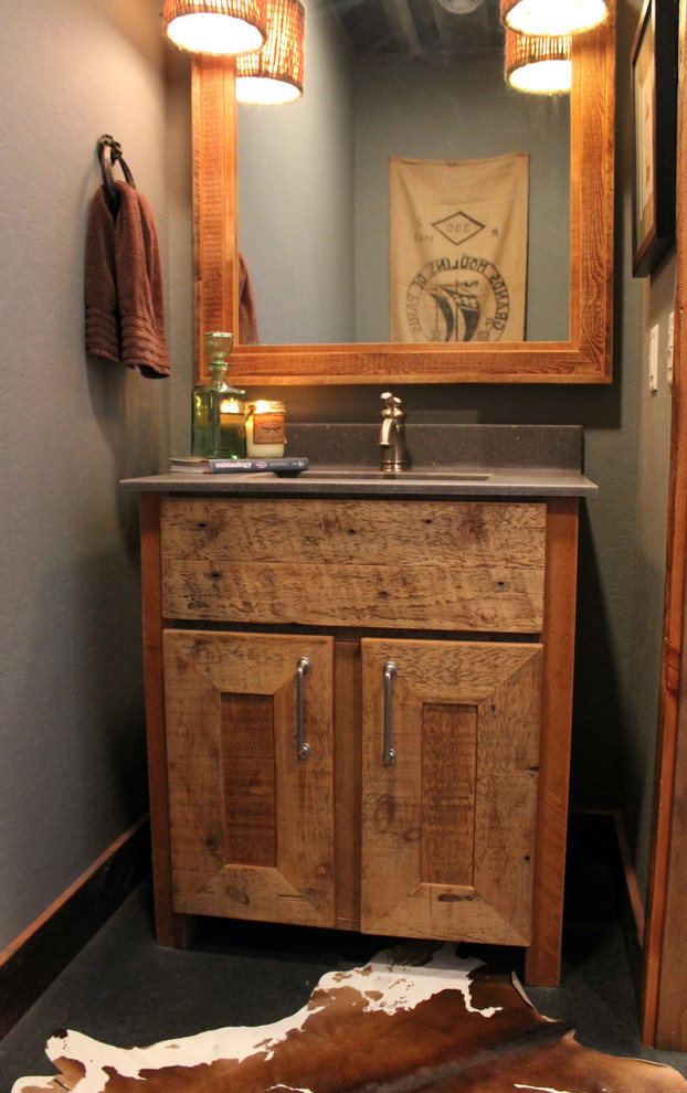 Cette photo montre une petite salle d'eau montagne en bois vieilli avec un lavabo intégré, un placard avec porte à panneau encastré, un plan de toilette en béton, WC séparés, un mur gris et sol en béton ciré.