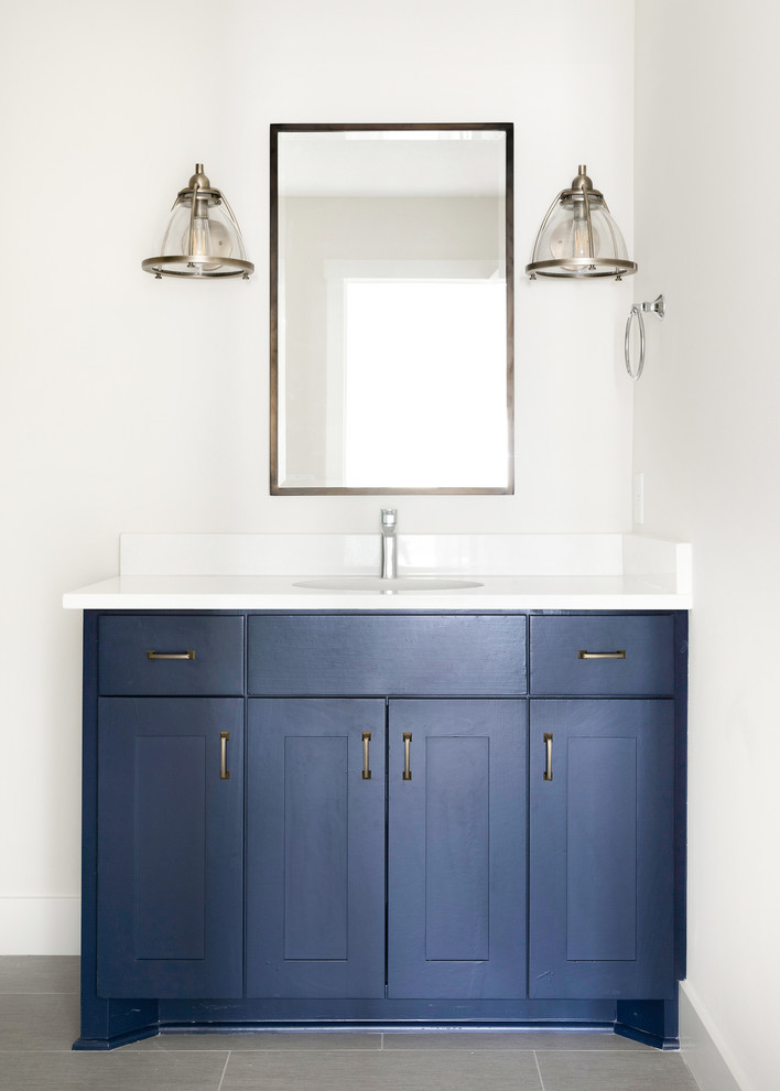 Photo of a medium sized classic bathroom in Minneapolis with shaker cabinets, blue cabinets, a submerged sink, quartz worktops, a hinged door, white worktops, white tiles, metro tiles, white walls, ceramic flooring, grey floors and a two-piece toilet.