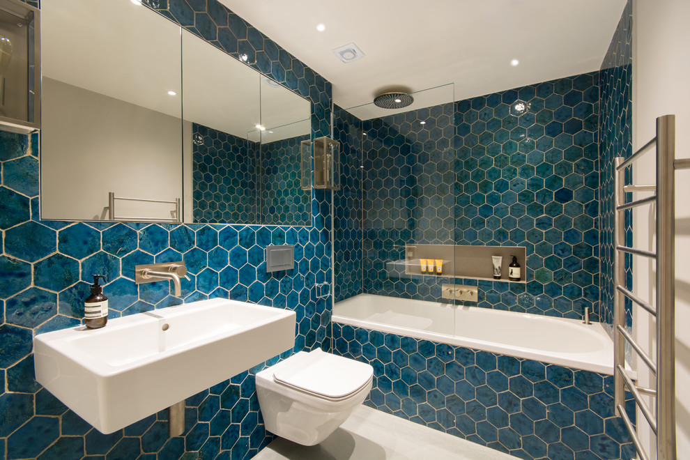 На фото: ванная комната в современном стиле с накладной ванной, душем над ванной, инсталляцией, синей плиткой, белыми стенами, бетонным полом, душевой кабиной, подвесной раковиной, серым полом и открытым душем с