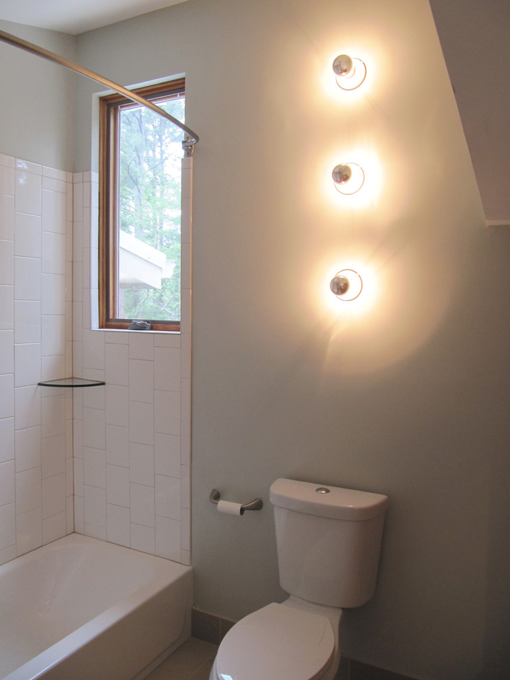 Cette photo montre une salle de bain moderne avec un combiné douche/baignoire, WC à poser et un mur gris.