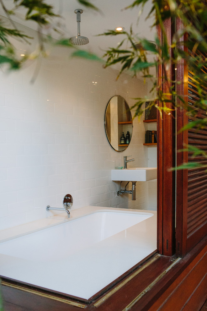 Modern inredning av ett badrum, med ett japanskt badkar, en dusch/badkar-kombination, vit kakel, vita väggar och ett väggmonterat handfat