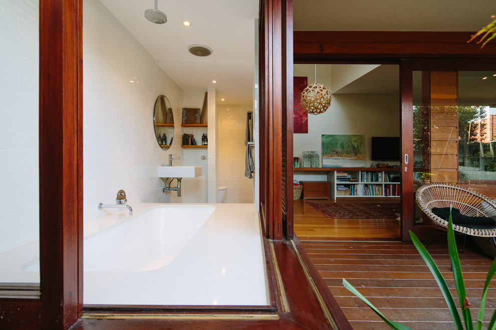 Пример оригинального дизайна: ванная комната в современном стиле с японской ванной, душем над ванной, белой плиткой, белыми стенами и подвесной раковиной