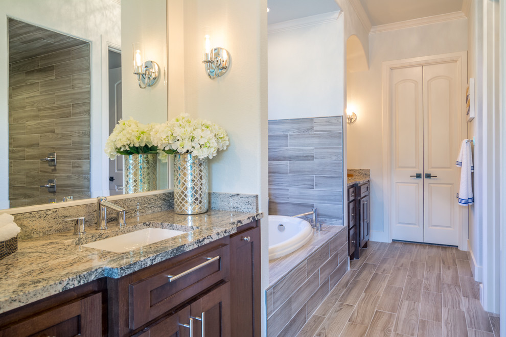 Design ideas for a classic ensuite bathroom in Dallas with recessed-panel cabinets, medium wood cabinets, a built-in bath, a corner shower, a two-piece toilet, grey tiles, ceramic tiles, grey walls, ceramic flooring, a submerged sink and granite worktops.