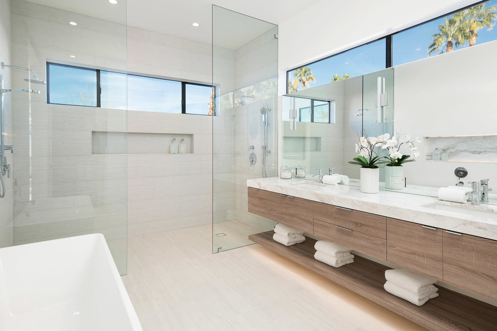 Cette image montre une salle de bain principale design en bois brun avec un placard à porte plane, une baignoire indépendante, une douche double, un carrelage beige, un mur blanc, un lavabo encastré, un sol beige et aucune cabine.