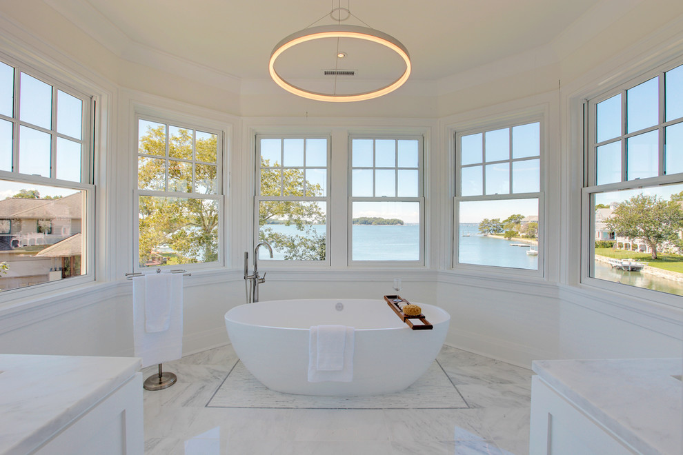 Foto de cuarto de baño principal costero con bañera exenta, paredes blancas, suelo de mármol y suelo blanco