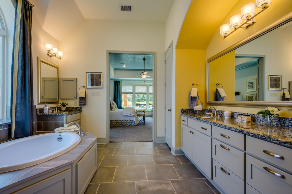 Cette photo montre une salle de bain chic avec un lavabo encastré, des portes de placard grises et une baignoire posée.