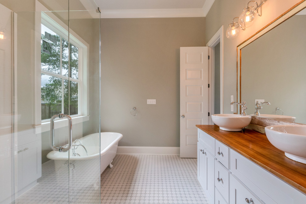 Aménagement d'une salle de bain principale classique avec un placard à porte shaker, des portes de placard blanches, une baignoire sur pieds, une vasque, un plan de toilette en bois et un sol gris.