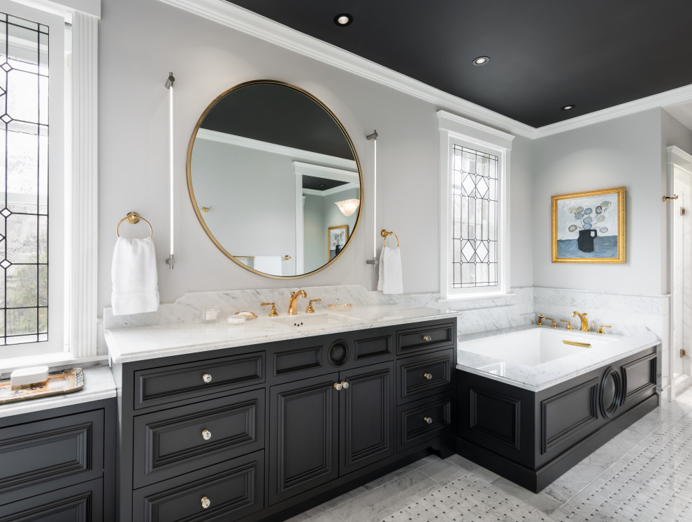 This is an example of an expansive traditional ensuite bathroom in Cincinnati with black cabinets, a submerged bath, grey tiles, grey walls, porcelain flooring, a submerged sink, grey floors, grey worktops, a single sink, a built in vanity unit and recessed-panel cabinets.