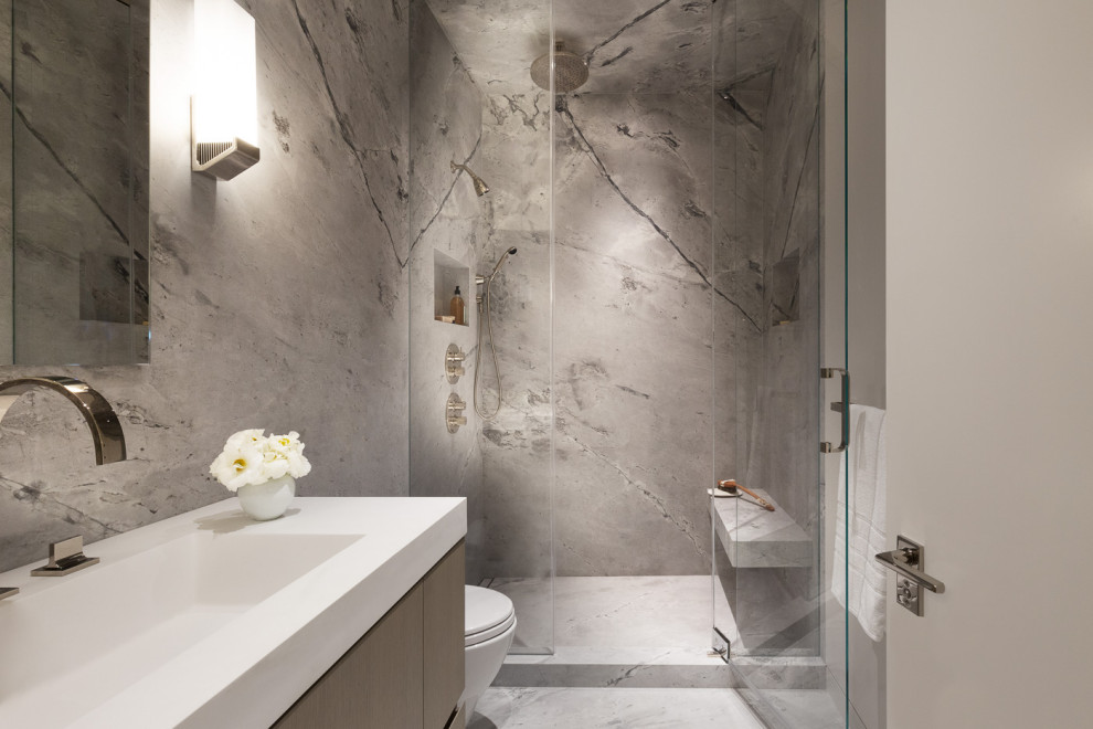 Photo of a contemporary shower room bathroom in San Francisco with flat-panel cabinets, an alcove shower, grey tiles, stone slabs, grey walls, an integrated sink, grey floors, a hinged door, white worktops, a shower bench and a single sink.